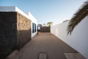a hallway of a white building with a stone wall at Casa Melián in Playa Blanca