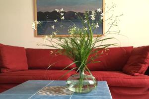 eine Vase mit Blumen auf einem Tisch vor einer roten Couch in der Unterkunft Aparthotel York in Hamburg