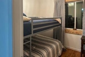 Ce lit superposé se trouve dans une chambre située à côté d'une fenêtre. dans l'établissement Cozy Maine Lakefront Cabin Rental, à Madawaska