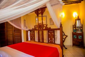 1 dormitorio con cama con dosel y sábanas rojas en Room Sawa, en Diani Beach