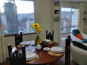 - une table à manger avec un vase et un tournesol dans l'établissement APARTAMENTO PRIVADO Piso 20a, CENTRICO, CERCA EMBAJADA USA, TELEFERICO, MALLS, VISTAS 360 y ZONA SEGURA, à La Paz