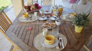 a wooden table with food and coffee cups on it at Chambre d'hôtes Ananda in Sisteron +24 photos