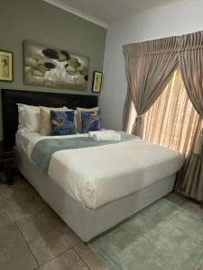 a bedroom with a large white bed with a window at Endonini House in Nelspruit