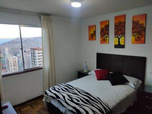 ein Schlafzimmer mit einem Bett und einem großen Fenster in der Unterkunft APARTAMENTO PRIVADO Piso 20a, CENTRICO, CERCA EMBAJADA USA, TELEFERICO, MALLS, VISTAS 360 y ZONA SEGURA in La Paz