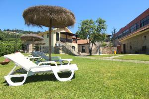 two lounge chairs and an umbrella in the grass at Aldeia do Tâmega in Amarante