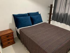 a bedroom with a bed with blue pillows and a window at Recanto da paz in Arraial do Cabo