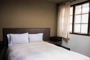a bedroom with a white bed and two windows at BB&B Hostel in La Paz