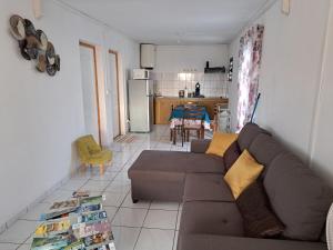 a living room with a brown couch and a kitchen at Appart a la res ANDY accueillant 1 A 5 PERS arrivé autonome , 2 PLACES de parking dans la cour devant la maison in Saint-Denis