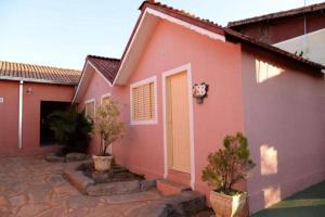 a pink house with a yellow door and some trees at Pousada Caldas Novas in Caldas Novas