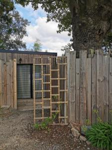 une clôture en bois avec une échelle à côté d'un bâtiment dans l'établissement Au Poème du Chêne, Logement indépendant, Intimité, SPA et bien-être, à Basse-Goulaine