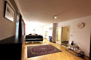 - un salon avec un canapé noir et un tapis dans l'établissement Cosy 4.5 rooms apartment @ LS 16 Dübendorf, à Dübendorf