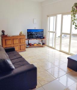 sala de estar con sofá y TV en Hostel Dela, en Tiradentes