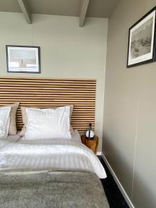 Schlafzimmer mit einem großen weißen Bett mit einem Kopfteil aus Holz in der Unterkunft Glacier Lodge Eqi in Ilulissat