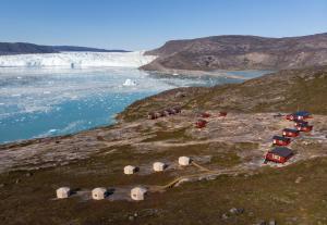 eine Gruppe von Zelten auf einem Hügel neben einem Wasserkörper in der Unterkunft Glacier Lodge Eqi in Ilulissat