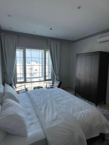 a large bed in a bedroom with a large window at Kama Place in Muscat