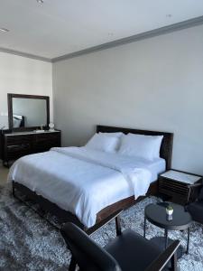a bedroom with a bed and a mirror and a chair at Kama Place in Muscat