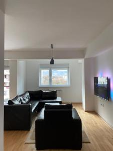 Apartment in Skopje في إسكوبية: غرفة معيشة مع أريكة سوداء وتلفزيون