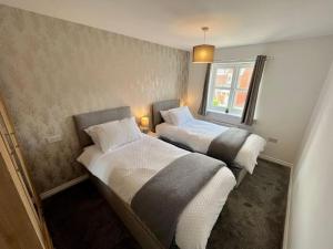 two beds in a small room with a window at Coral House by Blue Skies Stays in Thornaby on Tees