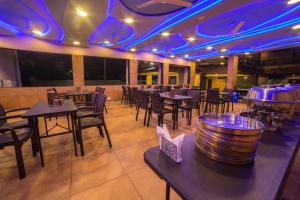 a restaurant with tables and chairs and purple lights at Amansaraa Bhide Retreat in Kīhīm