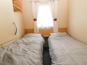2 camas en una habitación pequeña con ventana en 18 Chestnut Gardens, en Rhyl