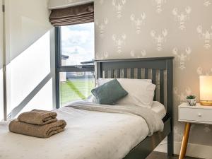 a bedroom with a bed and a window at Shearwater Lodge in Bamburgh