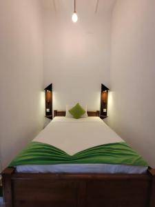 カトゥナーヤカにあるThe Empyrean Airport Transit Hotelのベッドルーム(緑のシーツを使用した大きな白いベッド付)