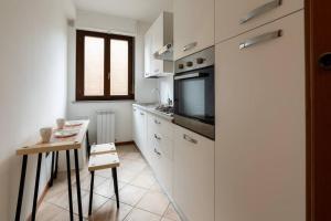 eine Küche mit weißen Schränken, einem Tisch und einem TV in der Unterkunft Mizar*B-Ampio Bilocale con parcheggio gratuito in Foligno