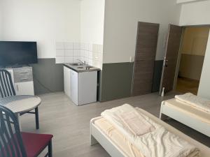 een kamer met een wastafel, een bed en een keuken bij Pension MC City in Gaimersheim