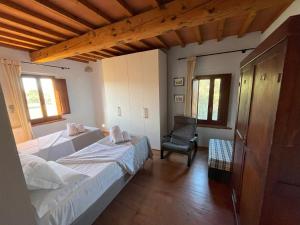 a bedroom with two beds and a chair at Nuvole Apartment in Lucignano