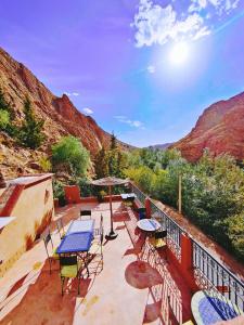 a patio with tables and chairs on a balcony with mountains at Auberge La Fibule Du Dades in Aït Idaïr