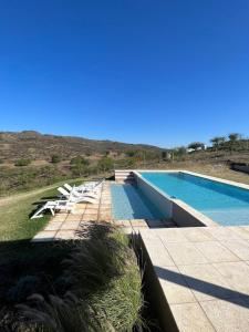 uma piscina com espreguiçadeiras brancas ao lado em el buen aire em La Pampa