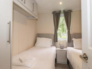 two beds in a small room with a window at Meadowsweet Lodge in Carnforth