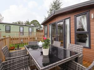 a patio with a table and chairs and a house at Meadowsweet Lodge in Carnforth