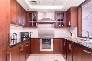a kitchen with wooden cabinets and a stove top oven at Bellavista - Striking - 1BR with Extra Twin Room - 29 boulevard - Partial Fountain View in Dubai