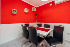 een rode eetkamer met een witte tafel en stoelen bij Apartments Lucija in Crikvenica