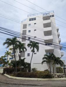 a white building with palm trees in front of it at Hastings Towers 3B Opp Sea 2 Bed 2 Bath in Bridgetown