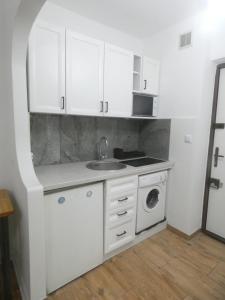 a white kitchen with a sink and a washing machine at Ator Apartament in Warsaw