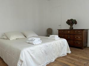 a bedroom with a bed with white sheets and a dresser at Les Hortensias in Épernay