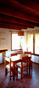 een eetkamer met een tafel, stoelen en ramen bij POSADA EL ROMANCE in Tandil