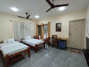1 dormitorio con 2 camas, mesa y escritorio en GREENVIEW HOMESTAY KOVALAM, en Trivandrum
