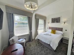 um quarto com uma cama, uma cadeira e janelas em ABBEY HOTEL em Stafford