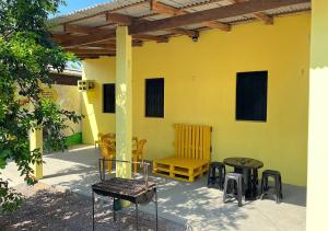 eine Terrasse mit Stühlen, Tischen und einer gelben Wand in der Unterkunft Casa Amarela in Presidente Figueiredo