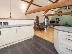 a kitchen with white cabinets and a living room at The Barn by Lyons in Talybont