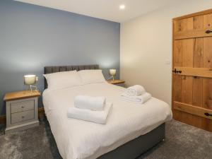 a bedroom with a large white bed with towels on it at The Barn by Lyons in Talybont