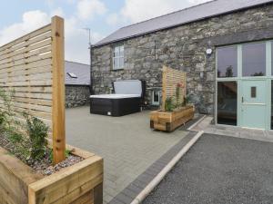 a patio with a stone building with a bath tub at The Barn by Lyons in Talybont