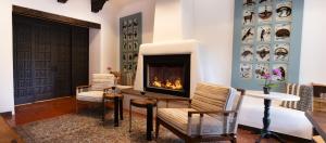 a living room with a fireplace and two chairs at Old Santa Fe Inn in Santa Fe