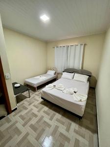 ヴェンダ・ノーヴァ・ド・イミグランテにあるCasa de sítio Caxixeのベッド2台とテーブルが備わる小さな客室です。