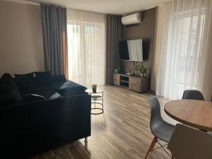 a living room with a black couch and a table at Apartament 4 Park City in Ostrów Wielkopolski