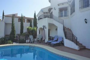 a villa with a swimming pool in front of a house at Los Tulipanes in Pego