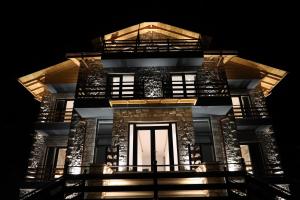 Un grand bâtiment avec des lumières allumées la nuit dans l'établissement Sofra Kolonjare, à Ersekë